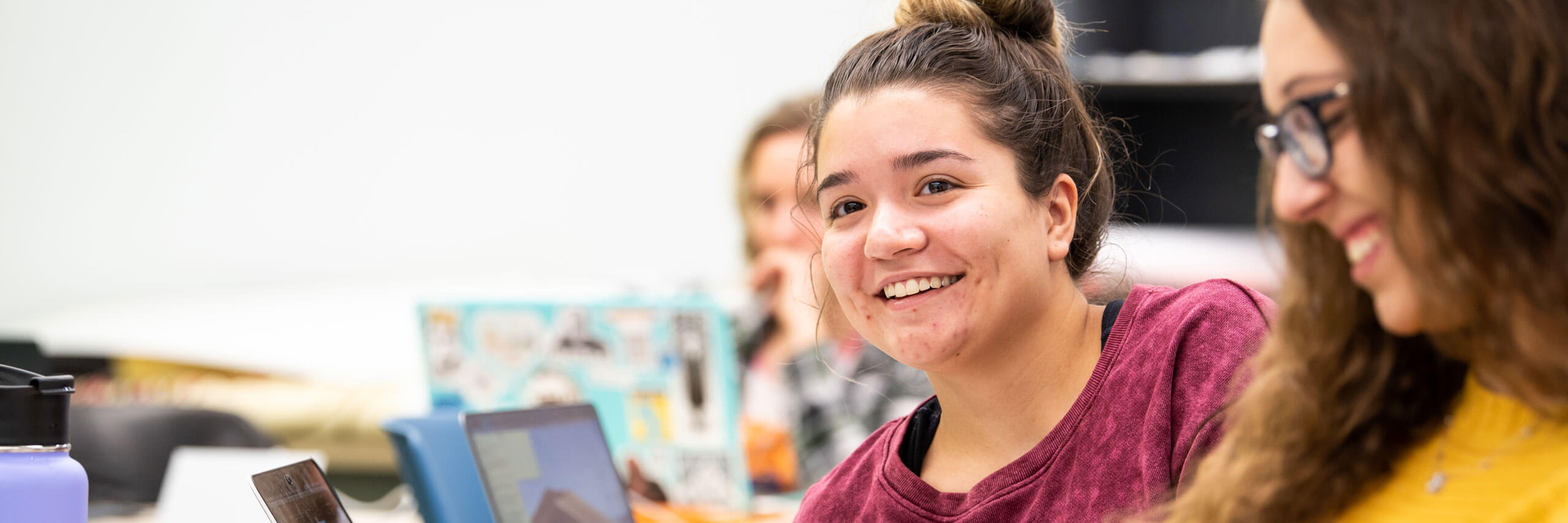 Students smile while while listening to a lecture.